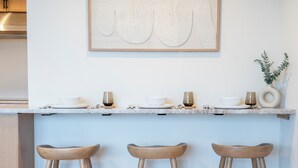 Une cuisine moderne avec un plan de travail bleu clair, trois tabourets en bois et une œuvre d’art encadrée accrochée au mur.
