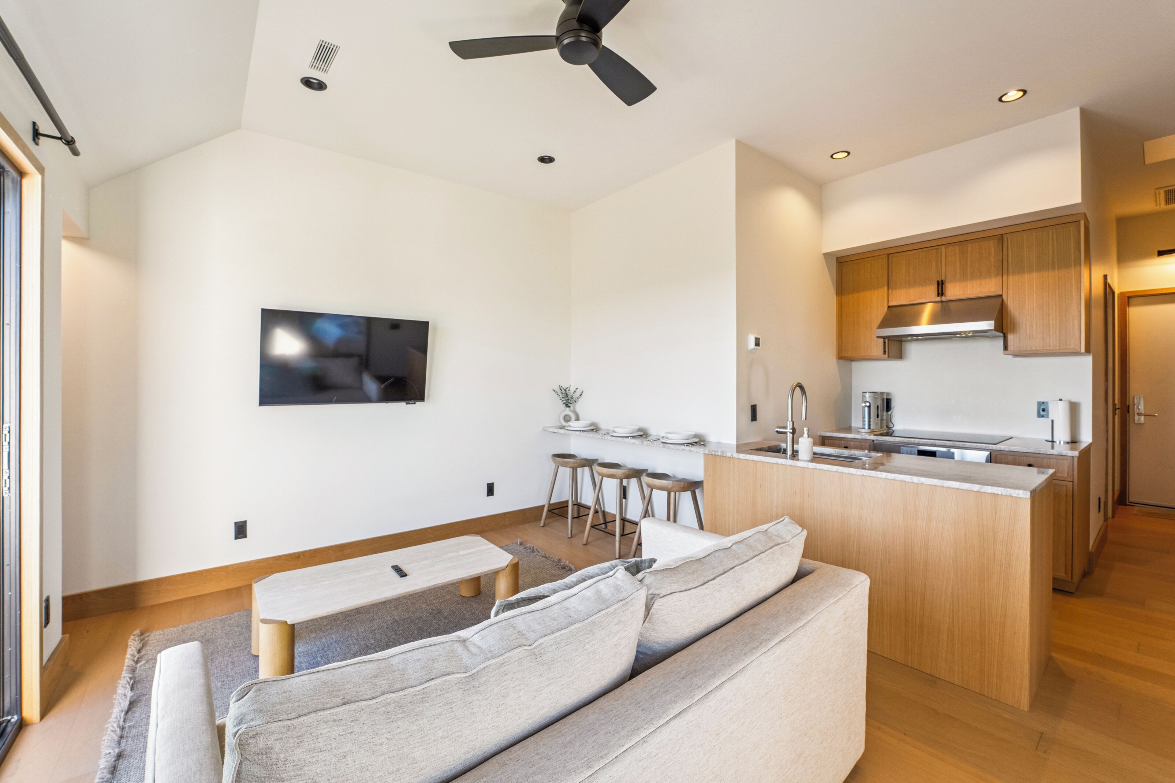 A modern living room with a sofa, a coffee table, and a TV mounted on the wall.