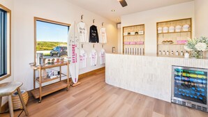 Un hall d’hôtel moderne avec un plancher en bois, un comptoir d’accueil, un présentoir de planches de surf et un réfrigérateur pour boissons.