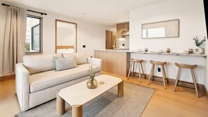 Un salon moderne avec un canapé, une table basse et des tabourets de bar.