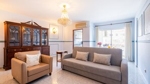 Un salon comprenant un canapé, un fauteuil, un meuble en bois et un lustre.