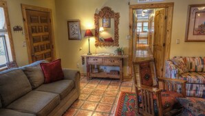 A cozy living room with a sofa, a wooden cabinet, and a patterned rug. - 4-bedroom house in Utopia with 450’ of private crystal clear Sabinal river front (Utopia)