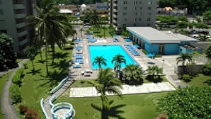 Un hotel con piscina, palmeras y vistas a una zona montañosa.