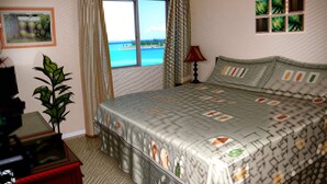 Un dormitorio con una cama grande, una ventana con cortinas, una planta y un cuadro en la pared.