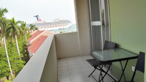 Un balcón con una mesa y silla de vidrio, piso de baldosas y vista a un crucero.