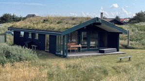Une maison moderne avec un toit végétalisé, de grandes fenêtres et une terrasse en bois.