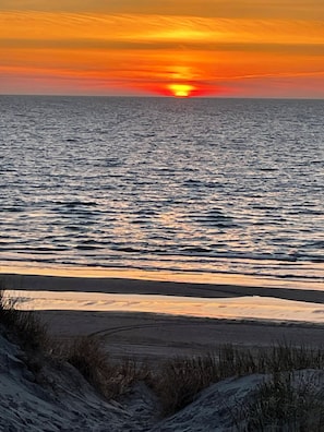 A sunset over the ocean with a beach in the foreground.