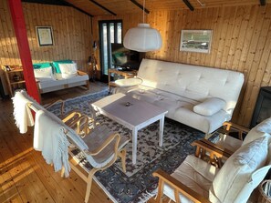 A cozy room with a sofa, chairs, a table, and a television.