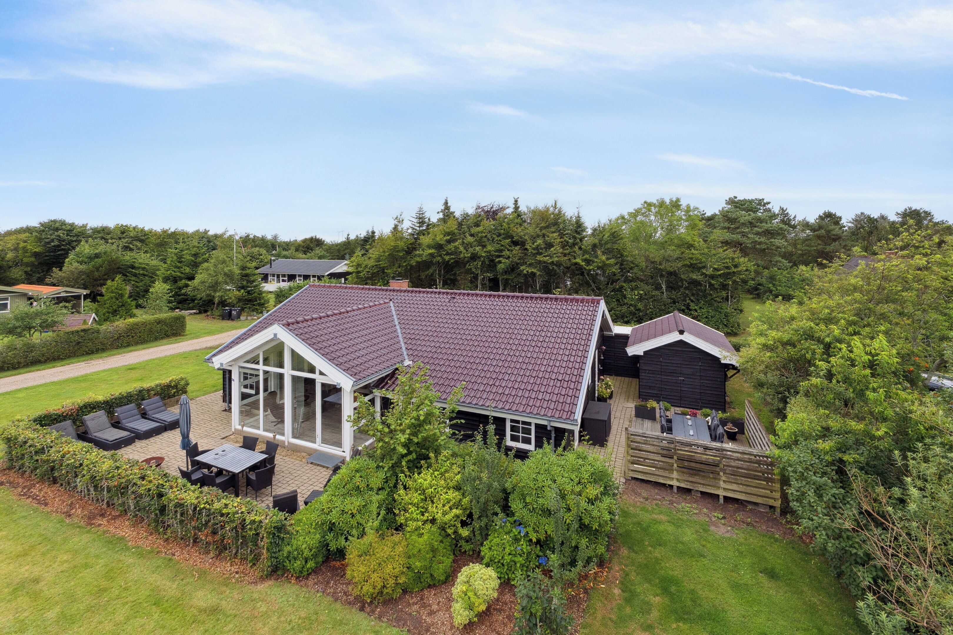 A house with a patio, a deck, and a large windowed room.