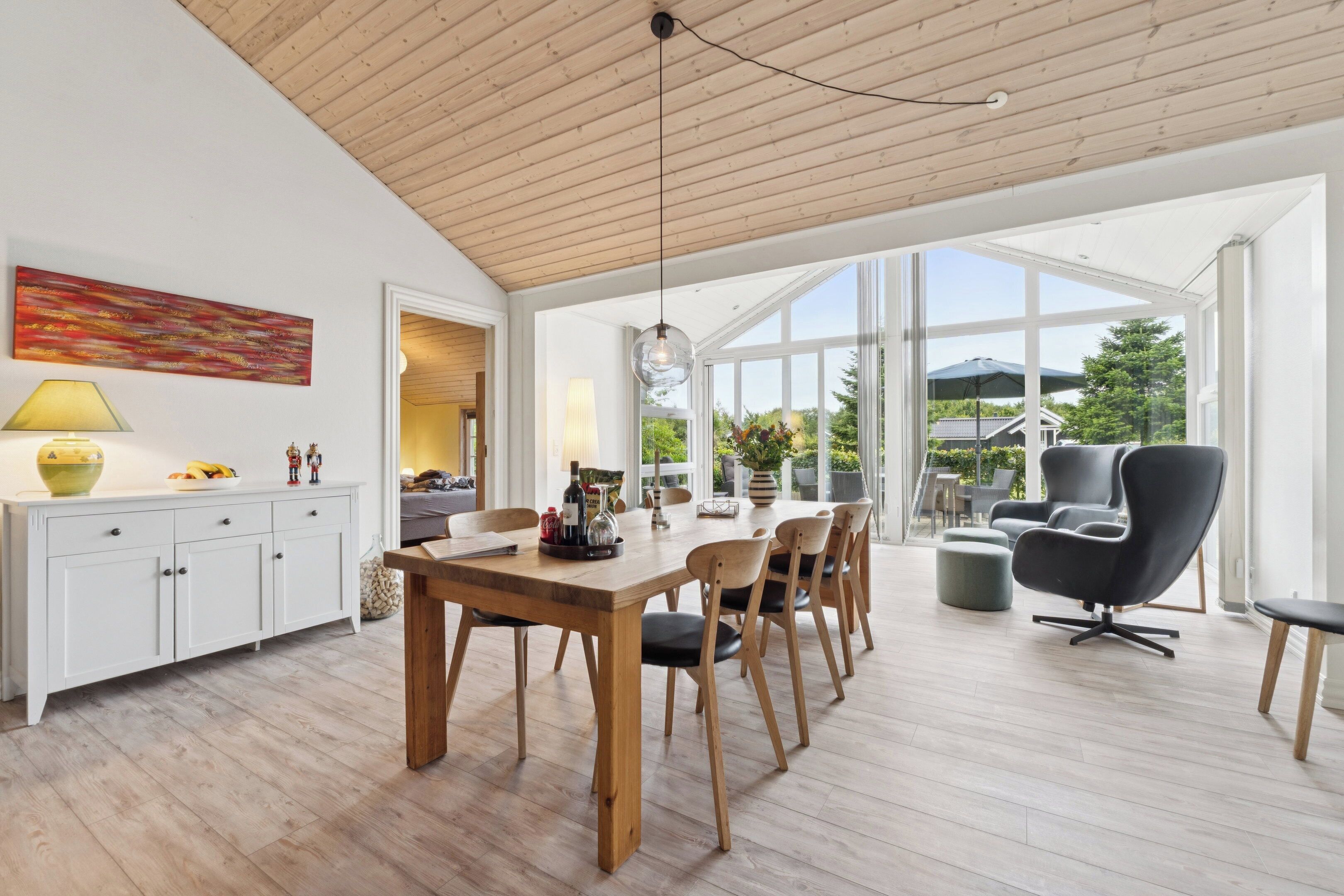 Een ruime eethoek met een houten tafel, stoelen en een groot raam met uitzicht op het omliggende landschap.