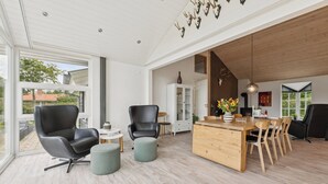 Un vaste espace de vie doté d’une grande fenêtre, d’une table à manger en bois et de meubles modernes.