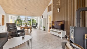 Un salon moderne doté d’une cheminée, d’un téléviseur et d’un coin repas baigné de lumière naturelle.