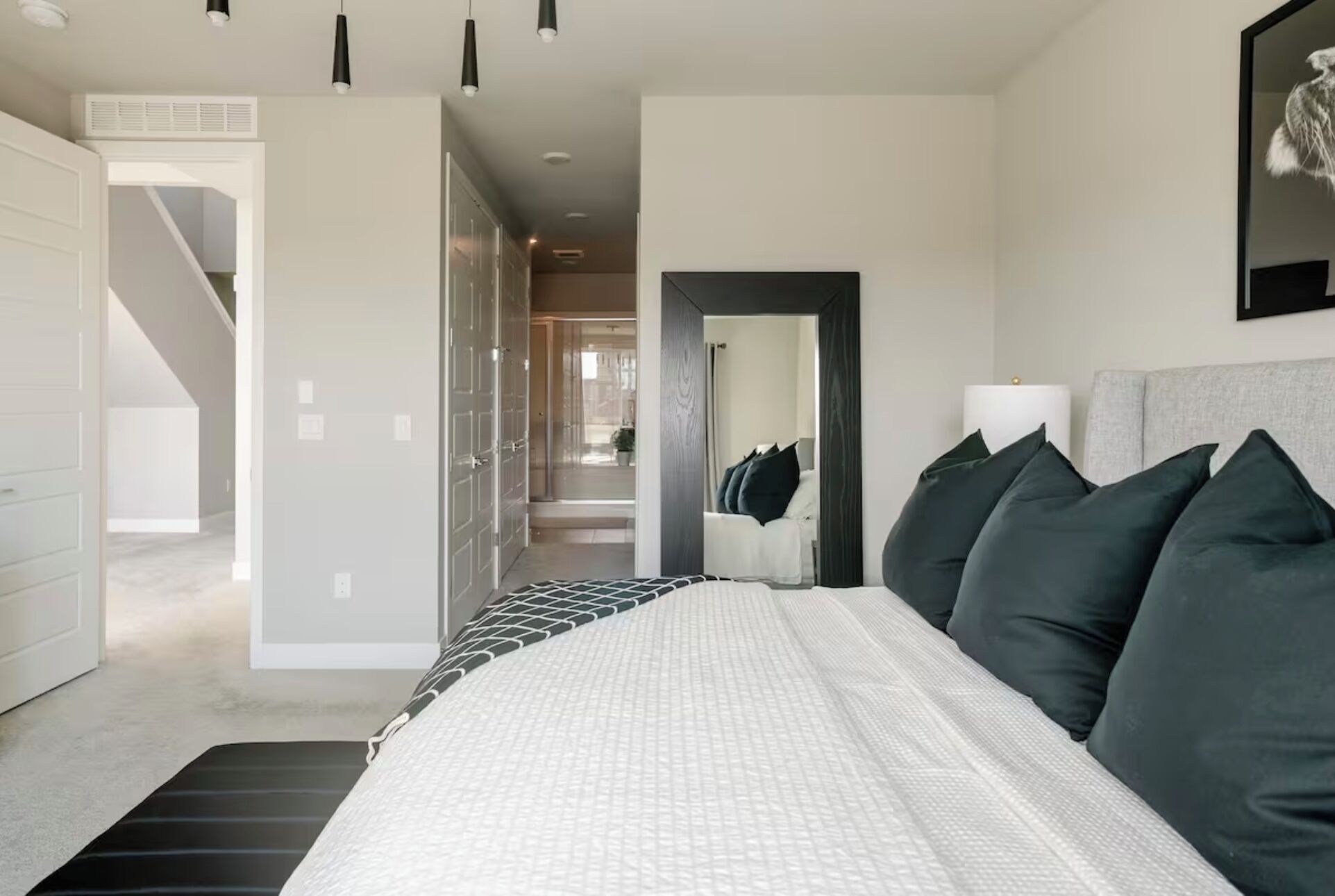 Een moderne slaapkamer met een groot bed, een inloopkast en een gang naar een badkamer.