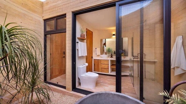 A modern bathroom with a glass door, a toilet, a sink, and a mirror.