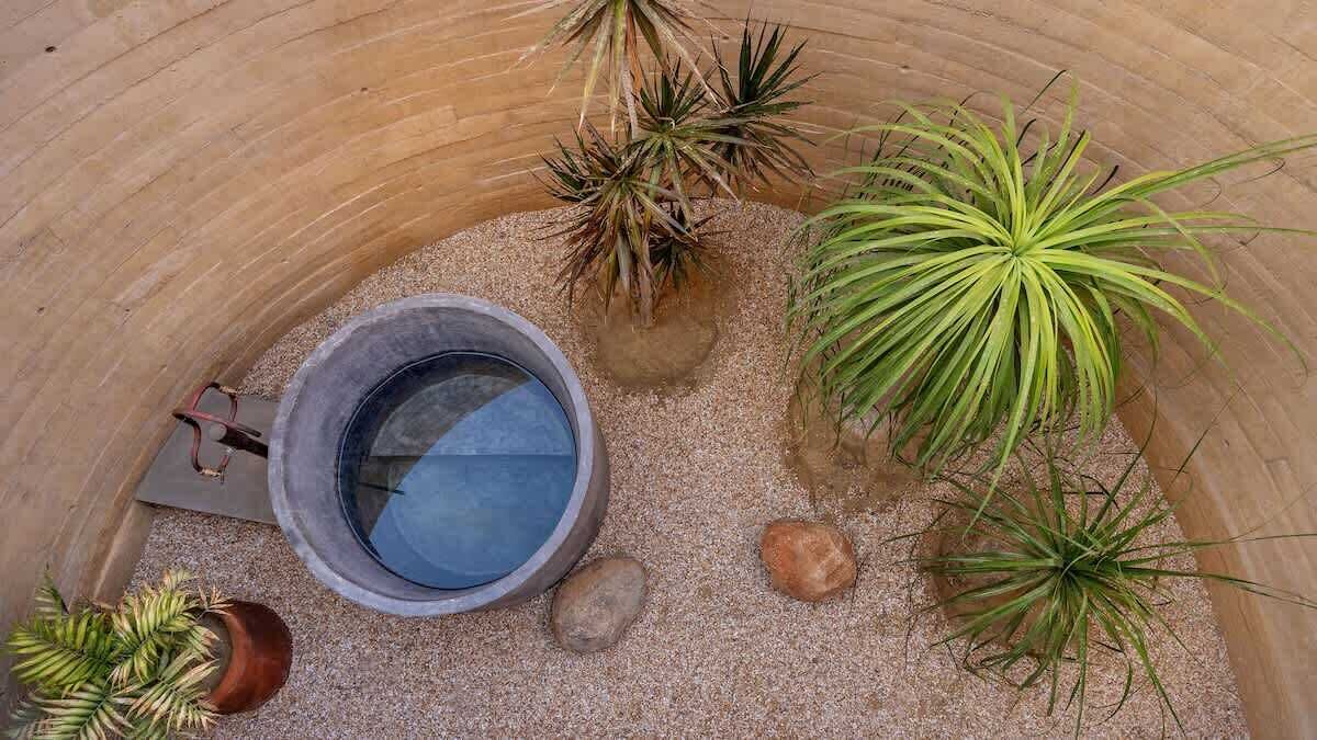 A circular structure with a water feature, surrounded by various potted plants.