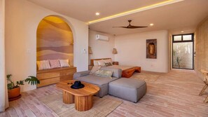 A modern living room with a sectional sofa, a wooden coffee table, and a ceiling fan. - WAMA Boutique Hotel - Depa Turrell (Todos Santos)