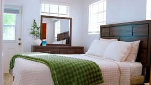 Une chambre à coucher avec un lit, une commode, un miroir et une fenêtre.