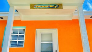 Un bâtiment à la façade orange, avec une porte blanche et une enseigne « Sunset Bay » au-dessus de l’entrée.