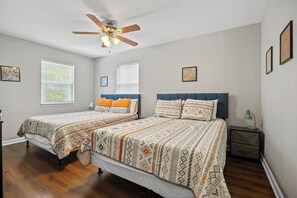 A bedroom with two beds, a ceiling fan, and a nightstand with a lamp.