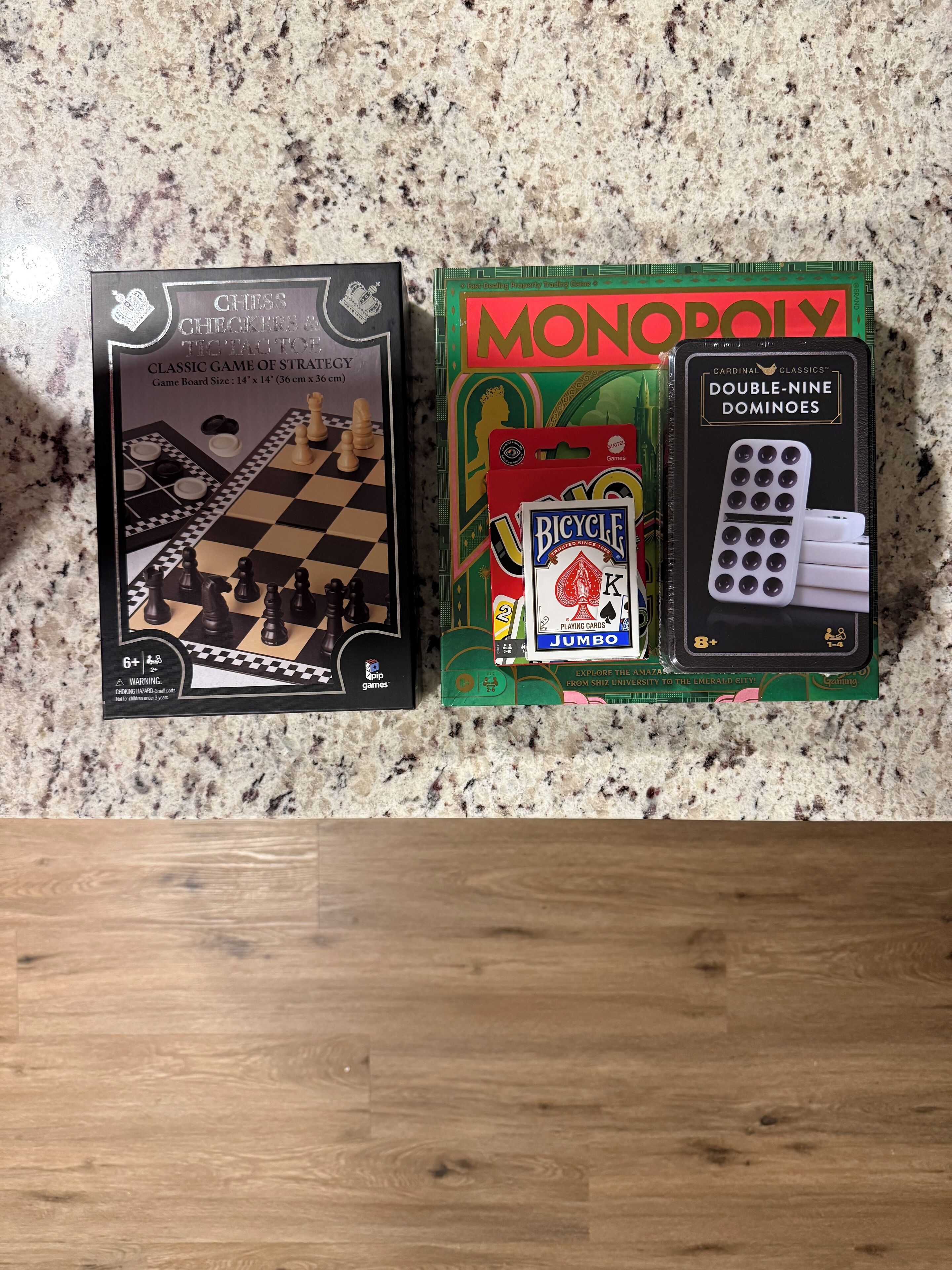 Un tablero para el juego de damas y Monopoly, una baraja de cartas Bicycle y dominó.