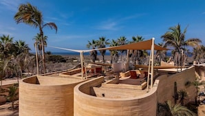 Un complexe hôtelier doté d’une piscine, de palmiers et offrant un paysage désertique.