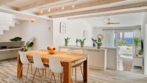 A modern kitchen with a wooden table, white chairs, and potted plants. - Bright oceanfront bungalow with views, garden and coastal style, 91 (San Miguel de Abona)