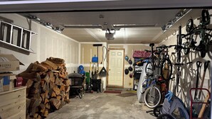 A garage with a concrete floor, wooden logs, a bicycle, and various tools. - The most affordable winter adventure stay in McCall!  (McCall)