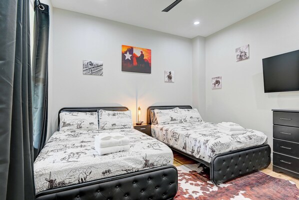 Une chambre avec deux lits, une télévision et des œuvres d’art accrochées au mur.