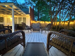 Eine Terrasse im Freien mit Korbmöbeln, Lichterketten und einem Holzdeck.