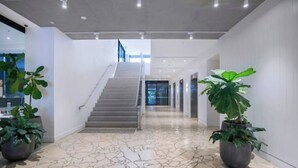 Een modern interieur met een trap naar een hoger verdiep, potplanten en een vloer met een patroon.