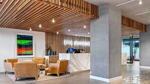 Een modern receptiegedeelte met een houten lambrisering, een marmeren receptiebalie en een zithoek met lederen stoelen.