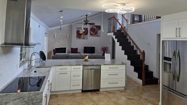 Una cocina moderna con una isla central, electrodomésticos integrados y una escalera que conduce a una zona loft.
