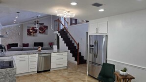 Una cocina moderna con una isla central, electrodomésticos de acero inoxidable y una escalera de madera.
