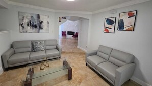 Una sala de estar con dos sofás grises, una mesa de centro de vidrio y arte abstracto en las paredes.