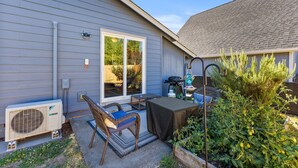 An outdoor patio with a covered table, a chair, and a grill. - Remodeled Albany 1BDRM, modern, pet friendly fenced yard, work station, laundry! (Albany)