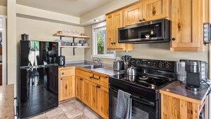 A modern kitchen with wooden cabinets, stainless steel appliances, and a window providing natural light. - Remodeled Albany 1BDRM, modern, pet friendly fenced yard, work station, laundry! (Albany)