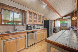 A kitchen with wooden cabinets, a dishwasher, a refrigerator, and a large window. - Lorel’s-Lake Area; Fenced for PETS; Mins to Downtown Rogers-Marina-Bike Trails (Little Flock)