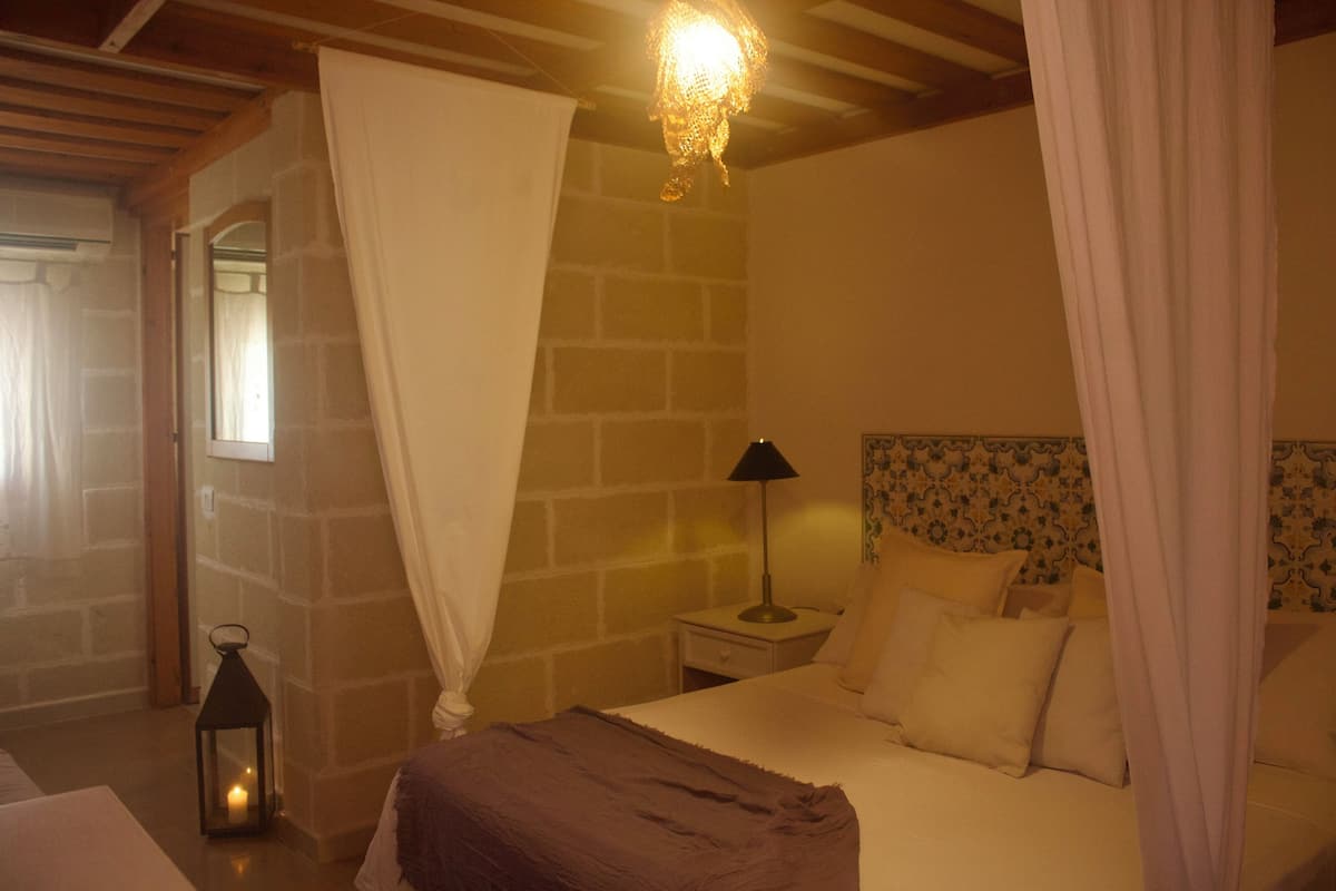 A bedroom with a bed, a nightstand, a lamp, a lantern, and a curtain.