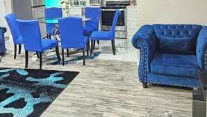A modern kitchen with white cabinets, a microwave, and a toaster. There is a blue sofa and a glass table with chairs. - Luxury basement, 3 bedrooms 2 bathrooms 4 beds sleep 8. Close to Falls (Niagara Falls)