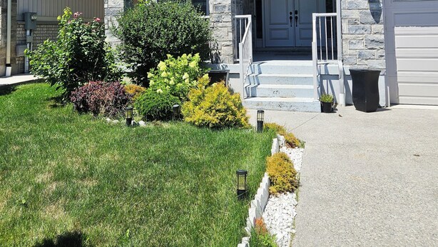 A two-story house with a stone facade, a front porch, and a garage. - Luxury basement, 3 bedrooms 2 bathrooms 4 beds sleep 8. Close to Falls (Niagara Falls)