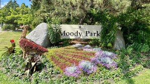 Een bordje voor Moody Park met een decoratief stuk rots en diverse kleurrijke bloemen.