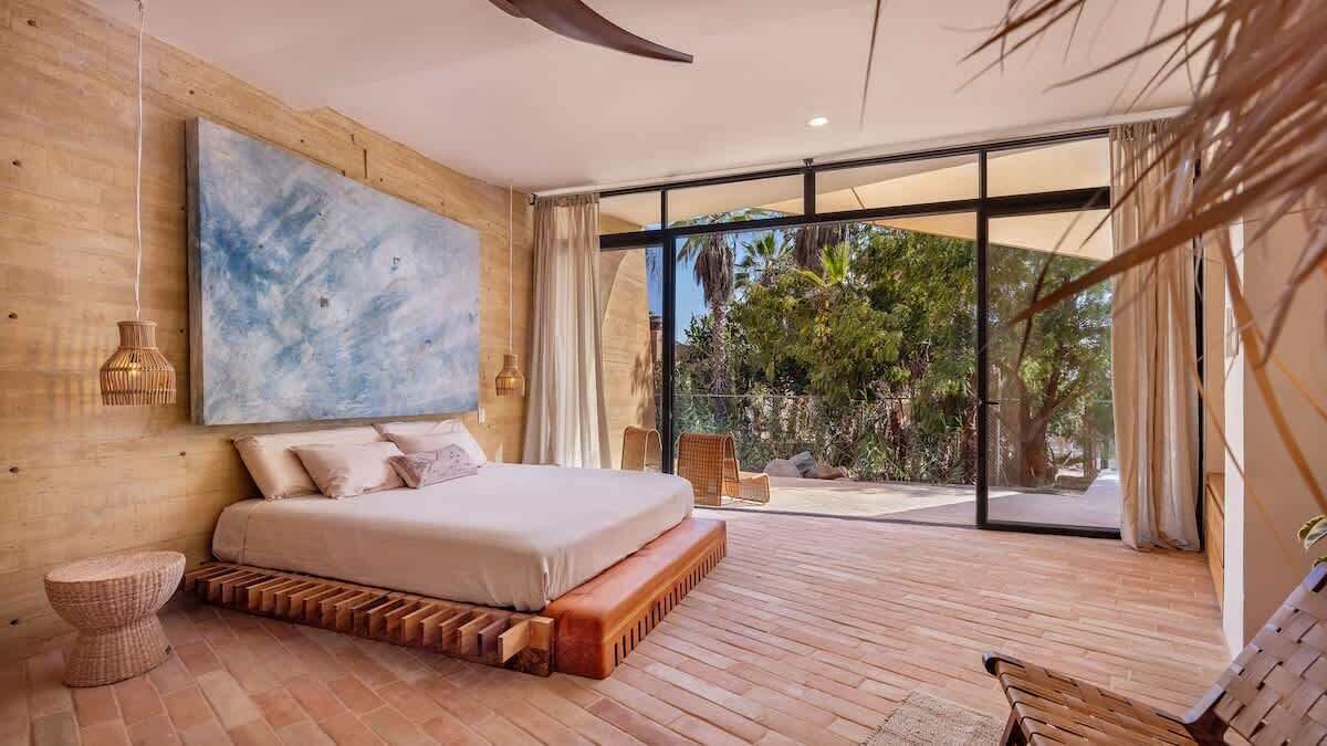 Un dormitorio moderno con una cama grande, vistas al exterior y un cuadro abstracto de gran tamaño en la pared.