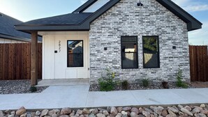 A two-story house with a stone facade, a dark roof, and a white door.