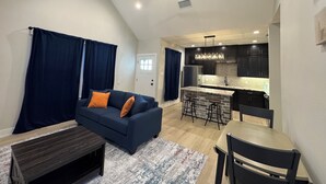 A modern living room with a dark blue sofa, a wooden coffee table, and a patterned rug.