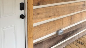 A wooden wall with a bear silhouette, a door, and a wall-mounted lantern. - “The Bear Cave” WhittleSticks Cabin in Lancing TN (Lancing)