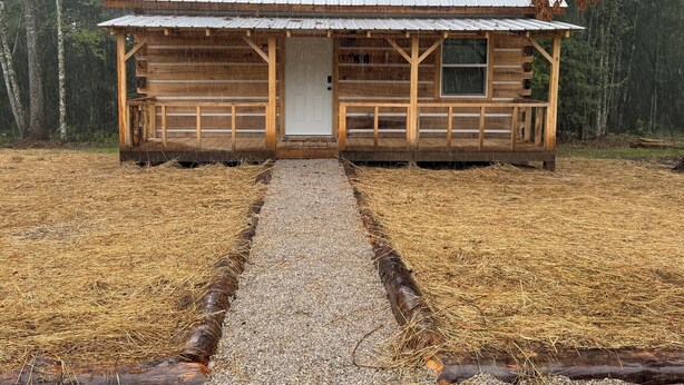A wooden cabin with a metal roof, a front porch, and a gravel path leading to the door. - “The Bear Cave” WhittleSticks Cabin in Lancing TN (Lancing)