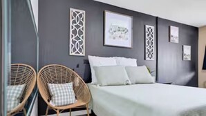 Ein Schlafzimmer mit einem Bett, zwei Korbstühlen und dekorativen Wandpaneelen.