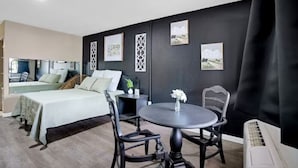 Ein modernes Hotelzimmer mit einem Bett, einem runden Esstisch und einem kleinen Beistelltisch.