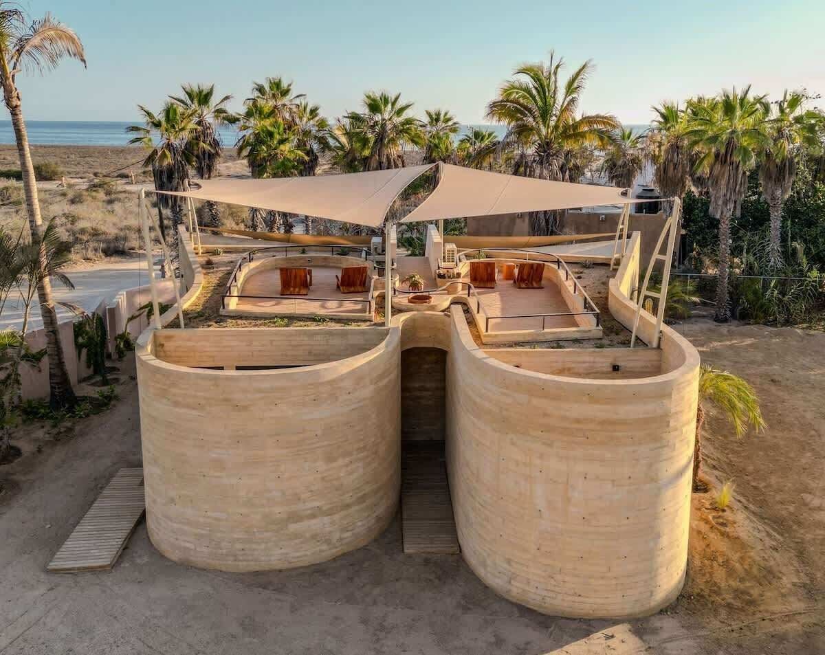 Una estructura frente a la playa con techo curvo y un acceso central.