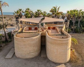 A beachside structure with a curved roof and a central passageway. - WAMA Boutique Hotel - Depa Davila (Todos Santos)